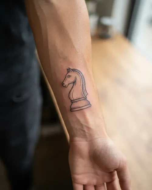 Fine-Line Schach-Springer-Tattoo am Unterarm, fotorealistische Nahaufnahme