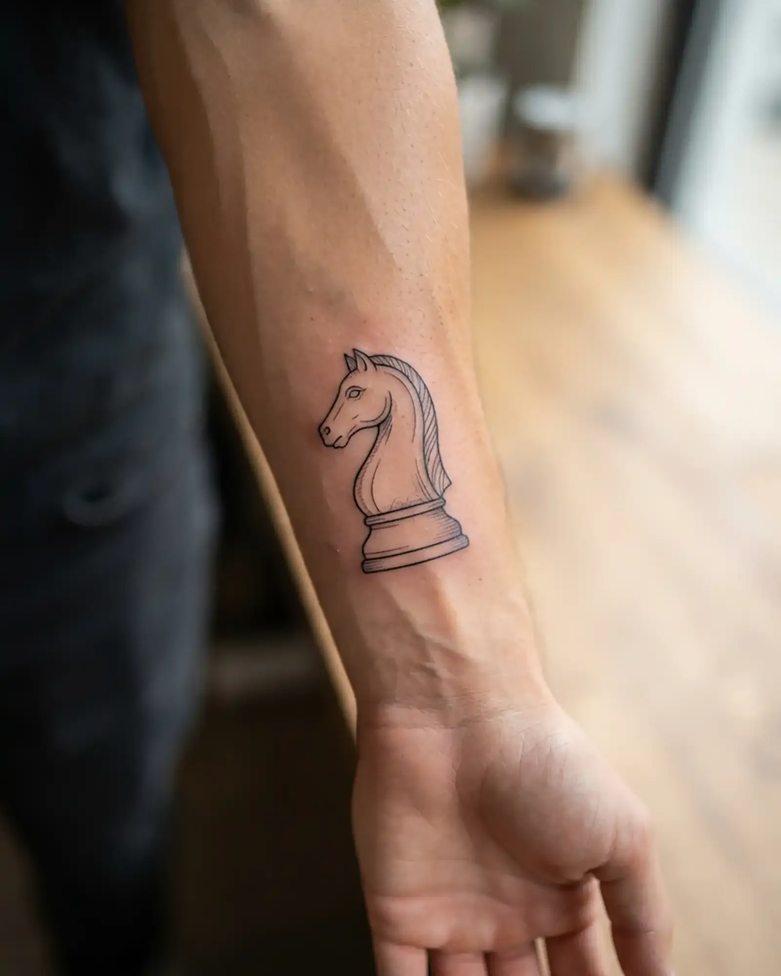 Fine-line chess knight tattoo on the forearm, photorealistic close-up