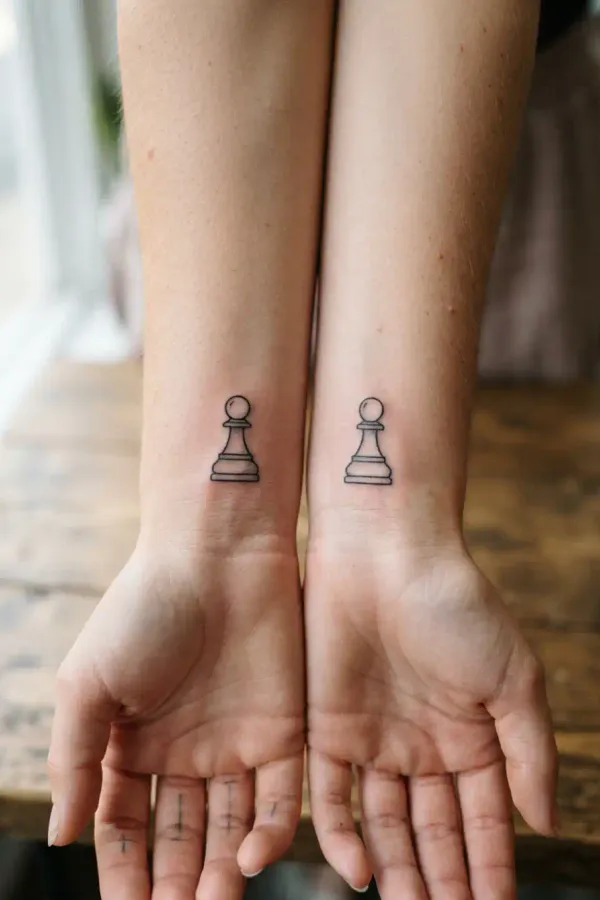 Two wrists with matching chess tattoos